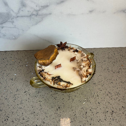 Decorative candle with herbs on a gray surface next to a marble wall