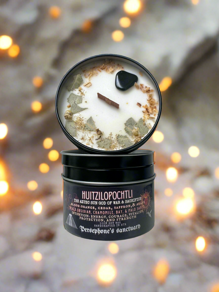 An intention candle with a wooden wick, open lid container, with visible botanical ingredients and a label that reads 'Huitzilopochtli'.